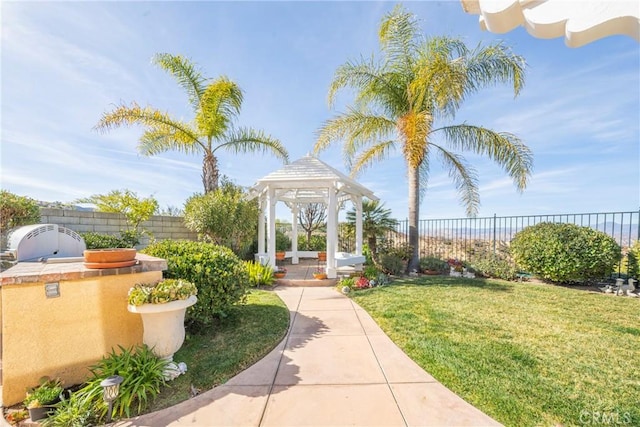 view of property's community featuring a gazebo, a yard, exterior kitchen, and a fenced backyard