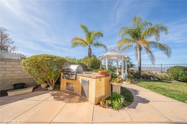 view of patio / terrace with exterior kitchen, a fenced backyard, a grill, and a gazebo