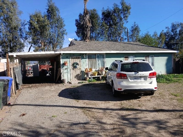 ranch-style house with a carport, driveway, and stucco siding