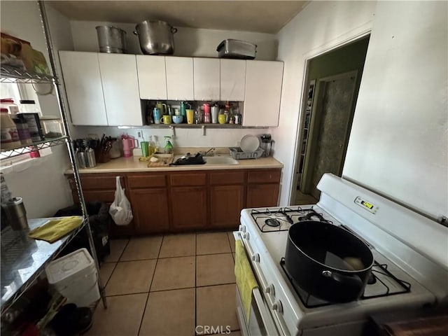 kitchen with light countertops, brown cabinetry, white cabinetry, and white range with gas stovetop