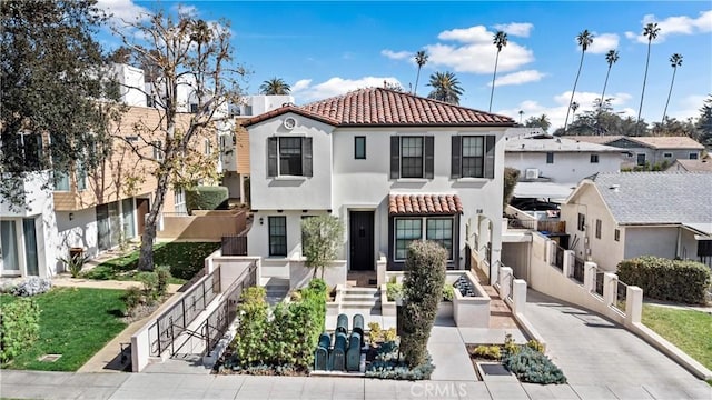 view of front of property featuring a tile roof, a residential view, fence, and stucco siding