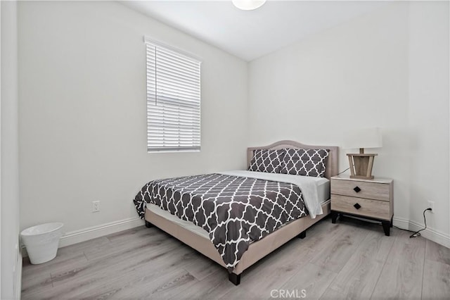 bedroom featuring light wood-type flooring, multiple windows, and baseboards