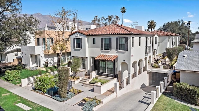 mediterranean / spanish house with aphalt driveway, fence, a tile roof, a residential view, and stucco siding