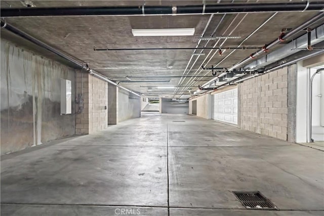 parking garage featuring electric panel, visible vents, and concrete block wall