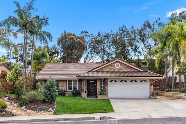 ranch-style house featuring a garage, a front yard, driveway, and a tiled roof