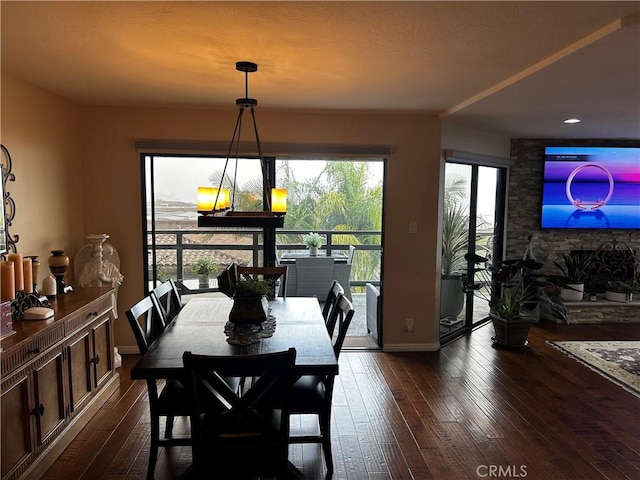 dining room with dark wood-style flooring, a fireplace, and baseboards