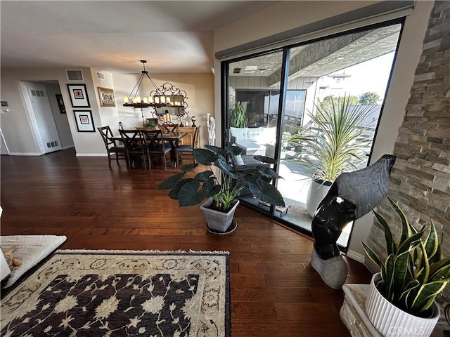 interior space with dark wood-style flooring, visible vents, a notable chandelier, and baseboards