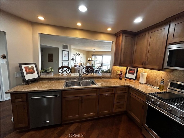 kitchen featuring visible vents, dark wood finished floors, appliances with stainless steel finishes, a peninsula, and a sink