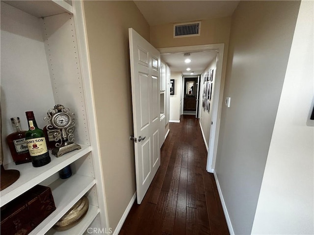 hall featuring dark wood finished floors, visible vents, and baseboards