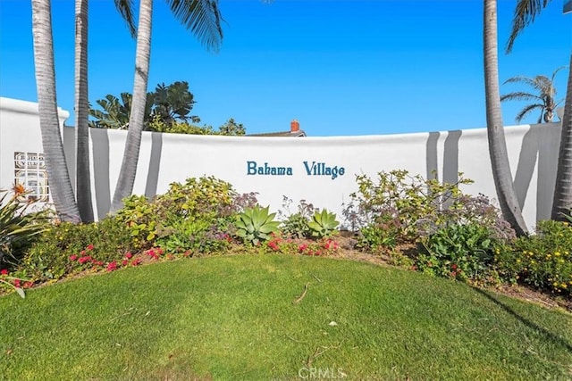 community / neighborhood sign with a lawn and fence