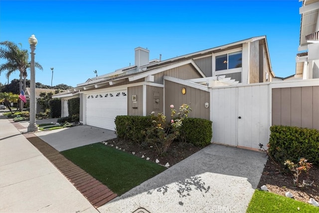 view of front facade featuring a garage, concrete driveway, fence, and a gate