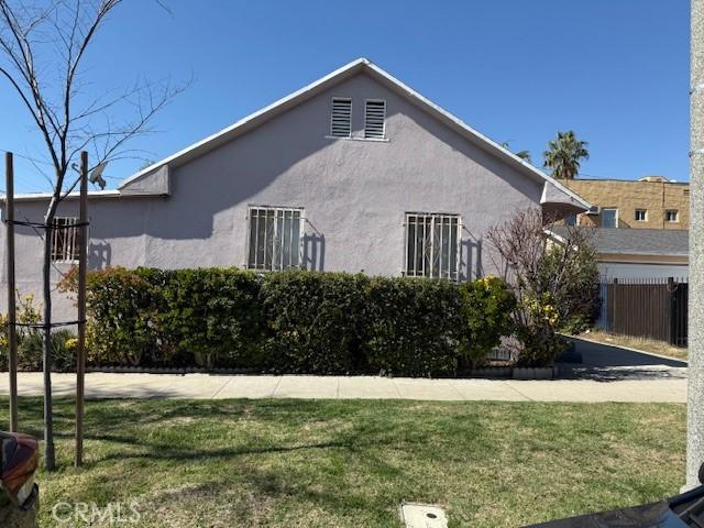 view of side of home featuring a lawn, fence, and stucco siding