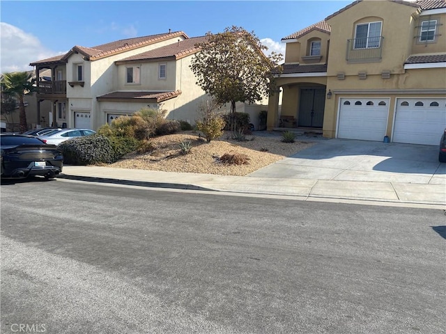 view of front of property featuring a garage, concrete driveway, a tiled roof, and stucco siding