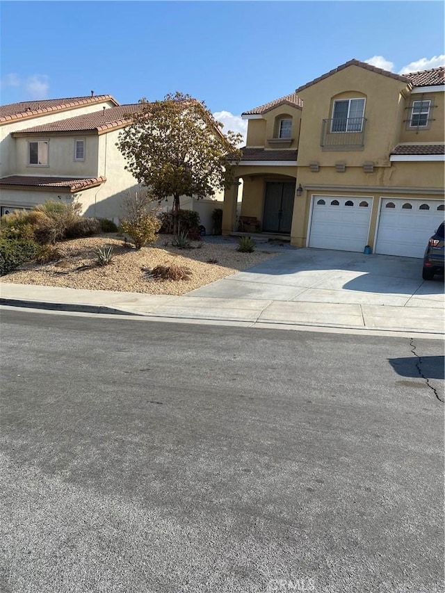 mediterranean / spanish-style house with a garage, a tiled roof, concrete driveway, and stucco siding