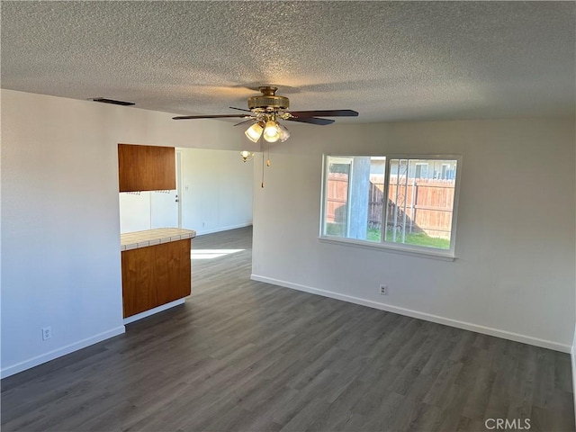 unfurnished room featuring dark wood-style floors, a textured ceiling, and baseboards