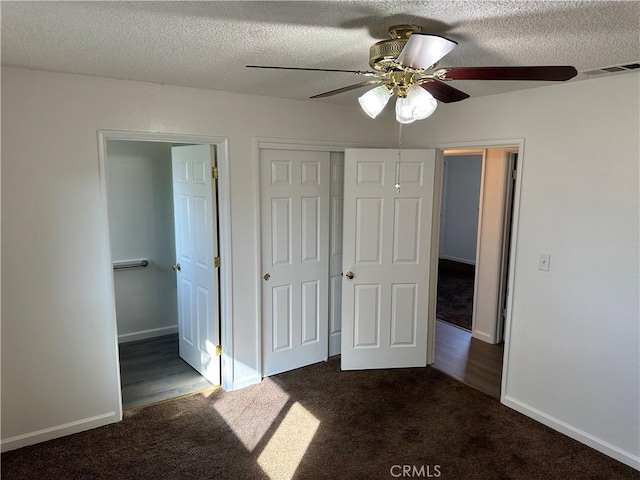 unfurnished bedroom featuring baseboards, dark colored carpet, and a textured ceiling