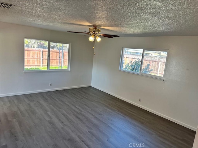 unfurnished room featuring baseboards, visible vents, dark wood finished floors, and a textured ceiling