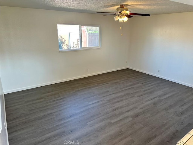 spare room with a textured ceiling, dark wood finished floors, and baseboards