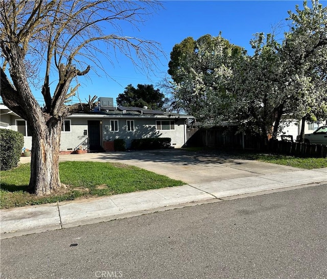 view of front facade with driveway, fence, and stucco siding