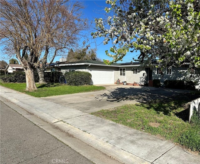 ranch-style home with a garage, concrete driveway, a front lawn, and stucco siding