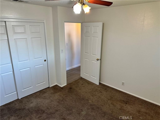 unfurnished bedroom featuring ceiling fan, a closet, dark carpet, and baseboards