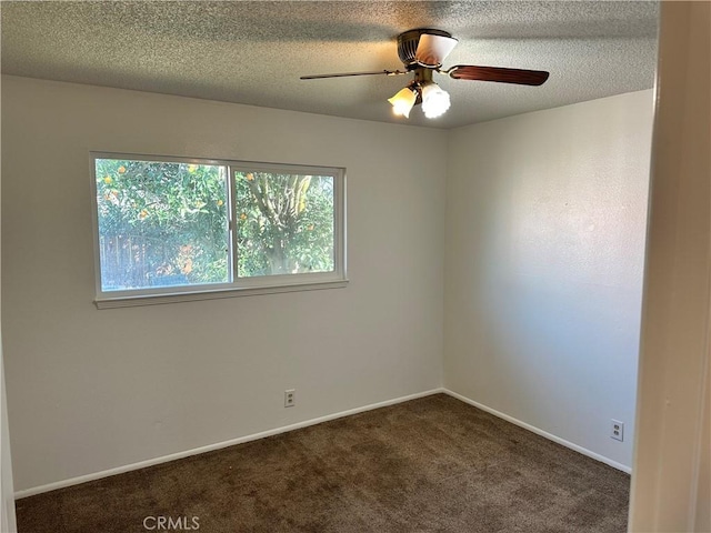 empty room with baseboards, dark carpet, ceiling fan, and a textured ceiling