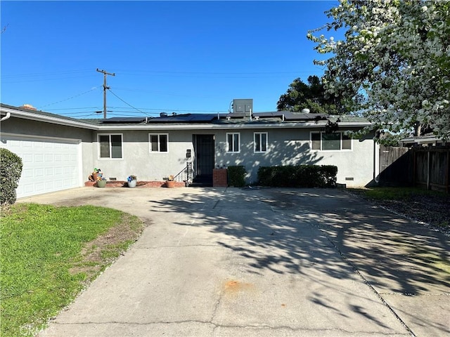 ranch-style house with entry steps, solar panels, fence, concrete driveway, and stucco siding