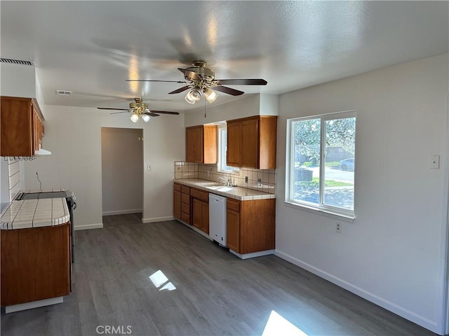 kitchen with brown cabinets, dishwasher, visible vents, and a sink