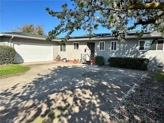 single story home featuring a garage, concrete driveway, crawl space, roof mounted solar panels, and stucco siding