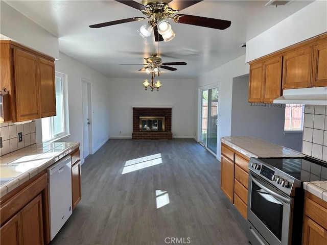 kitchen featuring tile counters, stainless steel range with electric cooktop, dishwasher, and under cabinet range hood