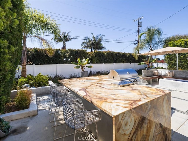 view of patio / terrace featuring a grill, outdoor dry bar, a fenced backyard, and area for grilling