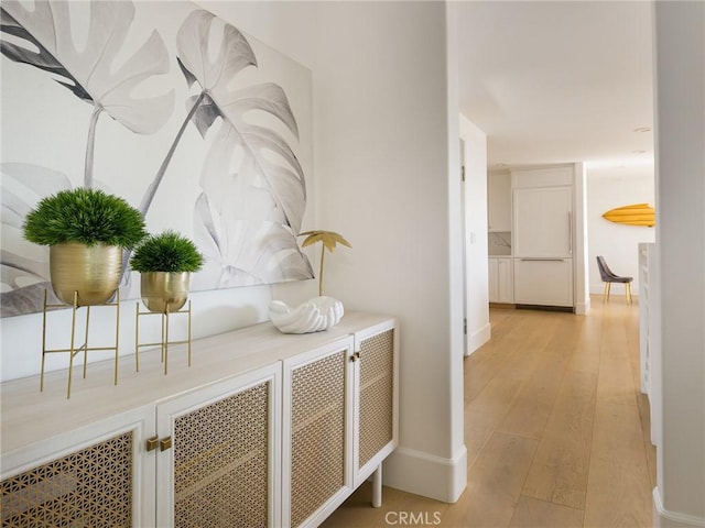 hall featuring light wood finished floors and baseboards