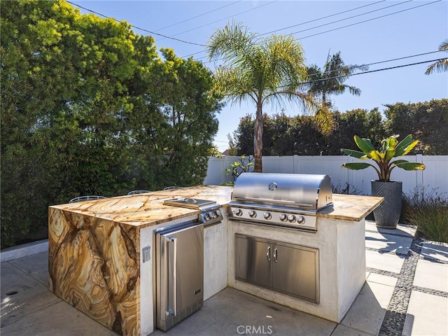 view of patio featuring area for grilling, fence, and an outdoor kitchen