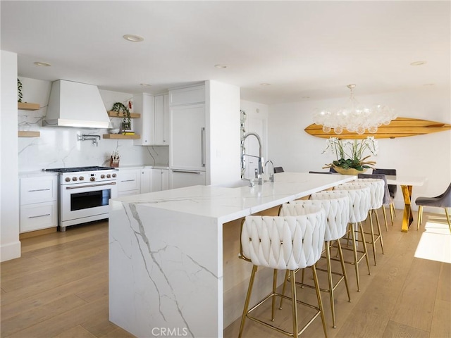 kitchen with open shelves, custom range hood, white cabinetry, light stone countertops, and high end stove