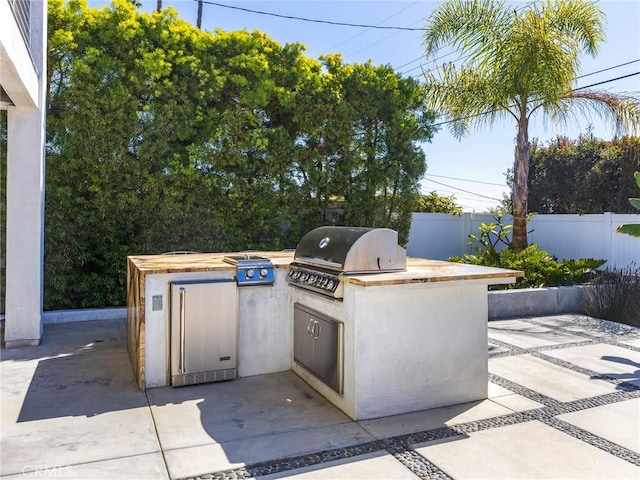 view of patio / terrace featuring exterior kitchen, a grill, and fence