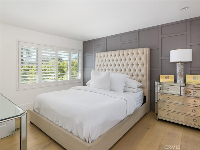 bedroom featuring light wood finished floors and a decorative wall