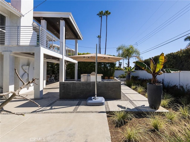 view of patio featuring fence and a balcony