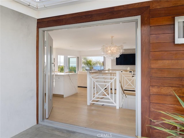 kitchen with light wood-style flooring, white cabinets, a notable chandelier, and light countertops