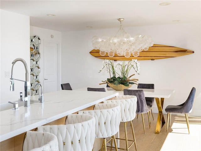 dining room with light wood-type flooring and a notable chandelier