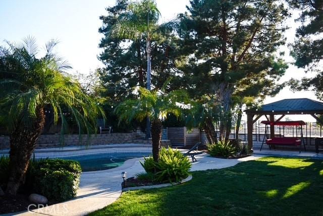 surrounding community with fence, a gazebo, a yard, a pool, and a patio area