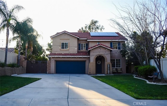 traditional-style home with concrete driveway, an attached garage, fence, roof mounted solar panels, and stucco siding