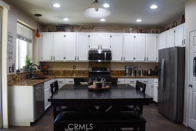 kitchen with hanging light fixtures, white cabinetry, appliances with stainless steel finishes, and a sink