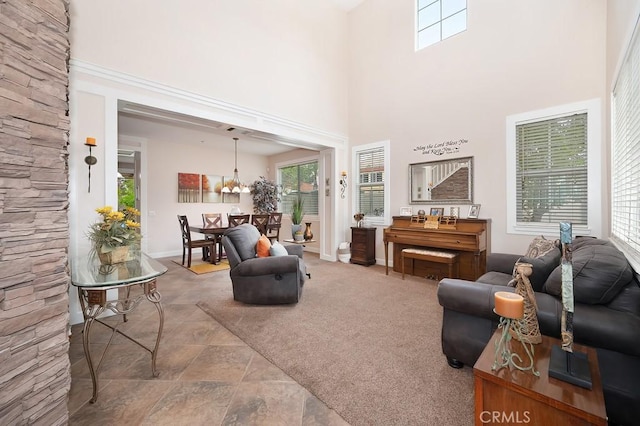 living area featuring baseboards, a chandelier, a towering ceiling, and plenty of natural light