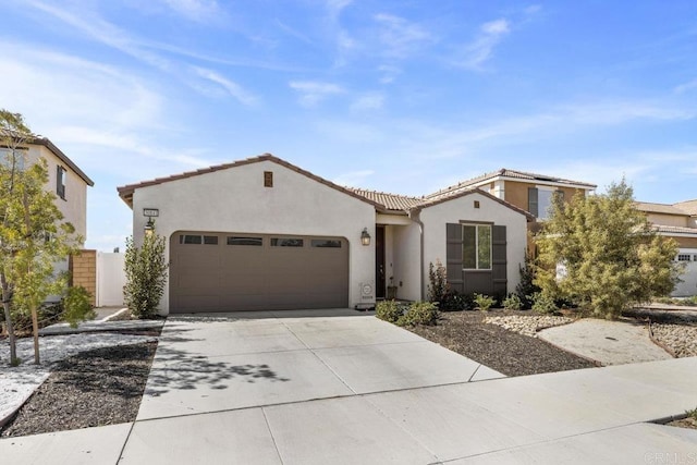 mediterranean / spanish home featuring concrete driveway, a tile roof, an attached garage, and stucco siding