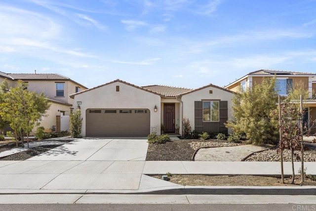 mediterranean / spanish home featuring a garage, driveway, a tiled roof, and stucco siding