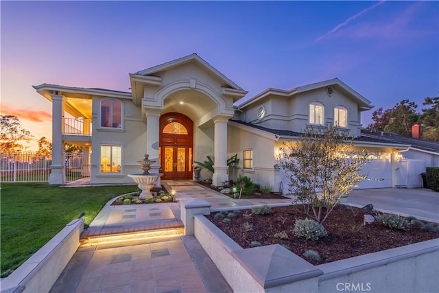 mediterranean / spanish-style house featuring driveway, a balcony, a yard, and stucco siding