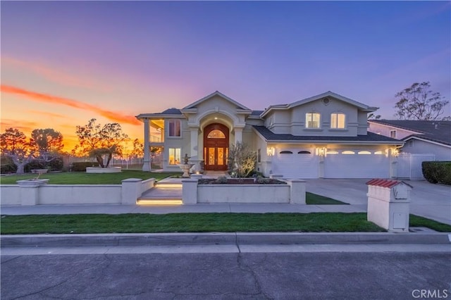 view of front facade with an attached garage, fence, concrete driveway, stucco siding, and a front yard