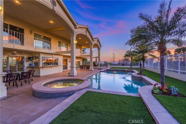 view of swimming pool with a pool with connected hot tub, a lawn, a patio area, fence, and an outdoor bar