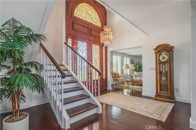 entryway featuring a chandelier, a high ceiling, dark wood-style flooring, baseboards, and stairs