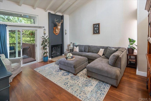 living room featuring dark wood-type flooring, baseboards, vaulted ceiling with beams, and a fireplace with flush hearth